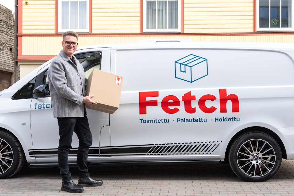 Kuljettaja paketin kanssa kuljetusauton vieressä